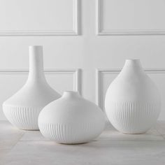 three white vases sitting on top of a table