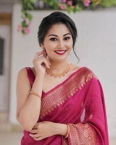 a woman in a pink sari posing for the camera with her hand on her cheek