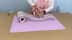 an older woman is cutting fabric on a table with scissors and a roll of tape