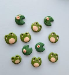 there are many green buttons with flowers on them and one has a frog's face