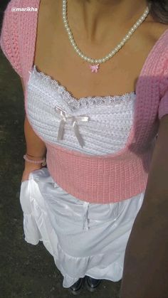 a woman wearing a pink sweater and white skirt