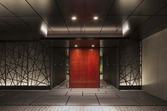 an empty room with red doors and tiled flooring in front of the door is lit by recessed lights