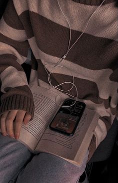 a person sitting down reading a book with headphones on