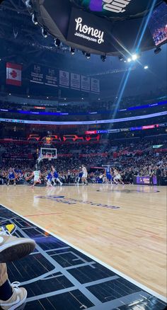 a basketball game is being played in an arena with people sitting on the floor watching