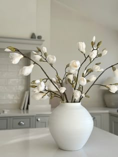 a white vase filled with flowers on top of a kitchen counter next to an oven