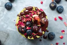 a cupcake with chocolate frosting and fruit toppings next to some blueberries