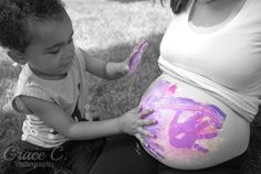 a black and white photo of a pregnant woman with her child's belly painted purple