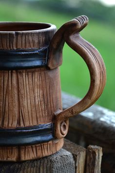 a wooden mug sitting on top of a wooden table next to a green grass field