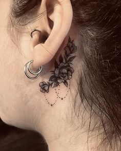 a woman's behind the ear has a flower tattoo on it