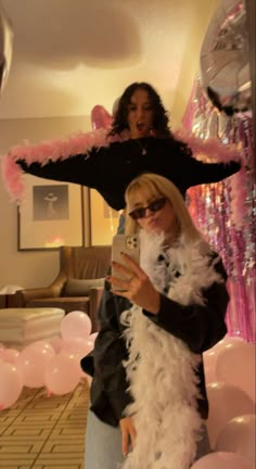 two women dressed in costumes standing next to each other and one holding a cell phone