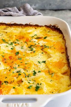 a casserole dish with cheese and vegetables in it on a tablecloth next to a fork