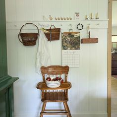 a wooden chair sitting in front of a wall filled with pictures and baskets on it