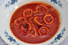 there is a bowl of soup with meat and onions in the red sauce on the plate