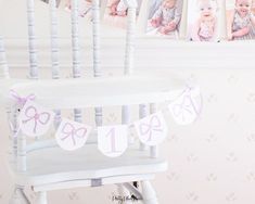 a baby's first birthday photo hanging on the wall next to a rocking chair