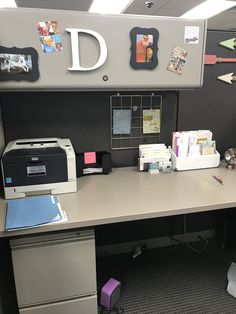 an office cubicle with a printer, file cabinet and other items on the desk