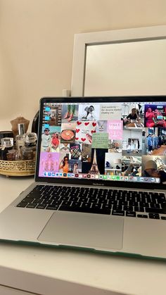 an open laptop computer sitting on top of a white desk next to a framed mirror