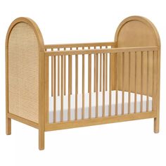 a wooden crib with a white mattress in it