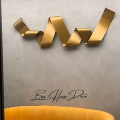 a yellow chair sitting in front of a wall with gold letters on it and the words big 4 classic brass