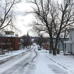 a snow covered street with houses and trees