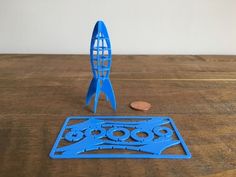 a blue plastic object sitting on top of a wooden table next to a penny coin