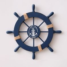 a blue ship's wheel with rope around it on a white wall behind the steering wheel