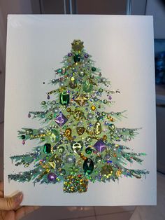 a hand holding up a card with a christmas tree made out of jeweled objects