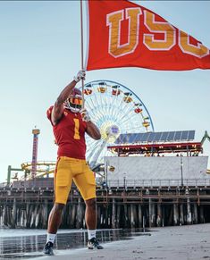 a man holding up a flag next to a ferris wheel with a red and yellow banner