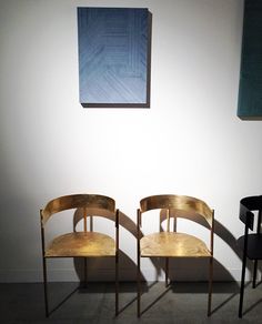 three chairs sitting next to each other in front of a wall with a painting on it