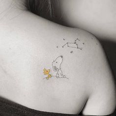 a woman's back shoulder with a small tattoo of a dog and the stars