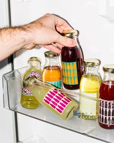 a person reaching into a refrigerator filled with different types of drinks and condiments