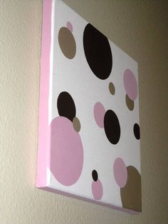 a pink and brown polka dot wall hanging on the wall next to a white wall