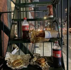 some food is sitting on a metal shelf near the street at night, and it looks like they are going to eat something