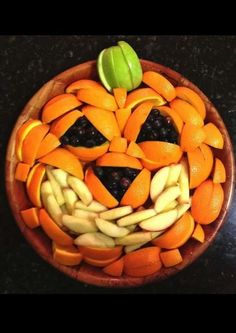 a wooden bowl filled with sliced up fruit and an orange shaped face on top of it