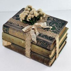 three old books stacked on top of each other with ribbons and flowers in the middle