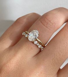 a woman's hand with a diamond ring on top of her finger and an engagement band