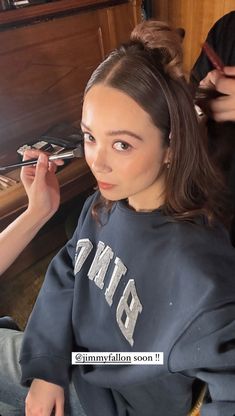 a woman is getting her hair done by someone