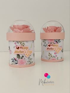 two small vases filled with pink flowers on top of a white table next to each other