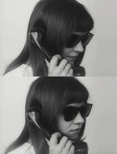 the woman is talking on her cell phone while wearing sunglasses and holding a pair of headphones to her ear