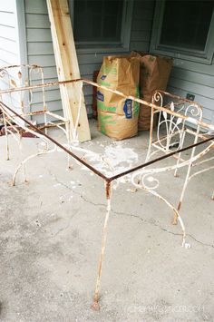 an old iron bed frame sitting on the side of a house next to a bag