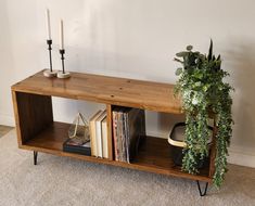 a wooden shelf with books and plants on it next to a wall mounted candle holder