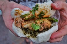 a person holding food in their hands with lots of green stuff on top of it