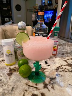 a pink drink sitting on top of a counter next to limes