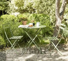 an outdoor table and two chairs in the shade