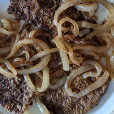 the meat and onions are being cooked on the plate in the bowl with sauce over it