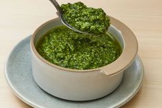 a spoon in a bowl filled with pesto