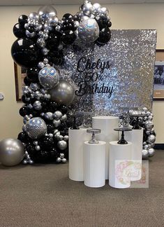 some black and silver balloons are on the floor next to two rolls of toilet paper