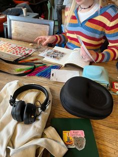 a young woman sitting at a table with headphones on and books in front of her