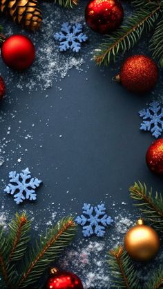 christmas ornaments and pine cones are arranged on a black surface with snow flakes, fir branches