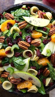 a salad with spinach, apples, cranberries and pecans in it