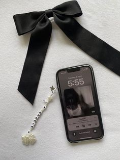 a cell phone with a black ribbon and a white flower on the side next to it